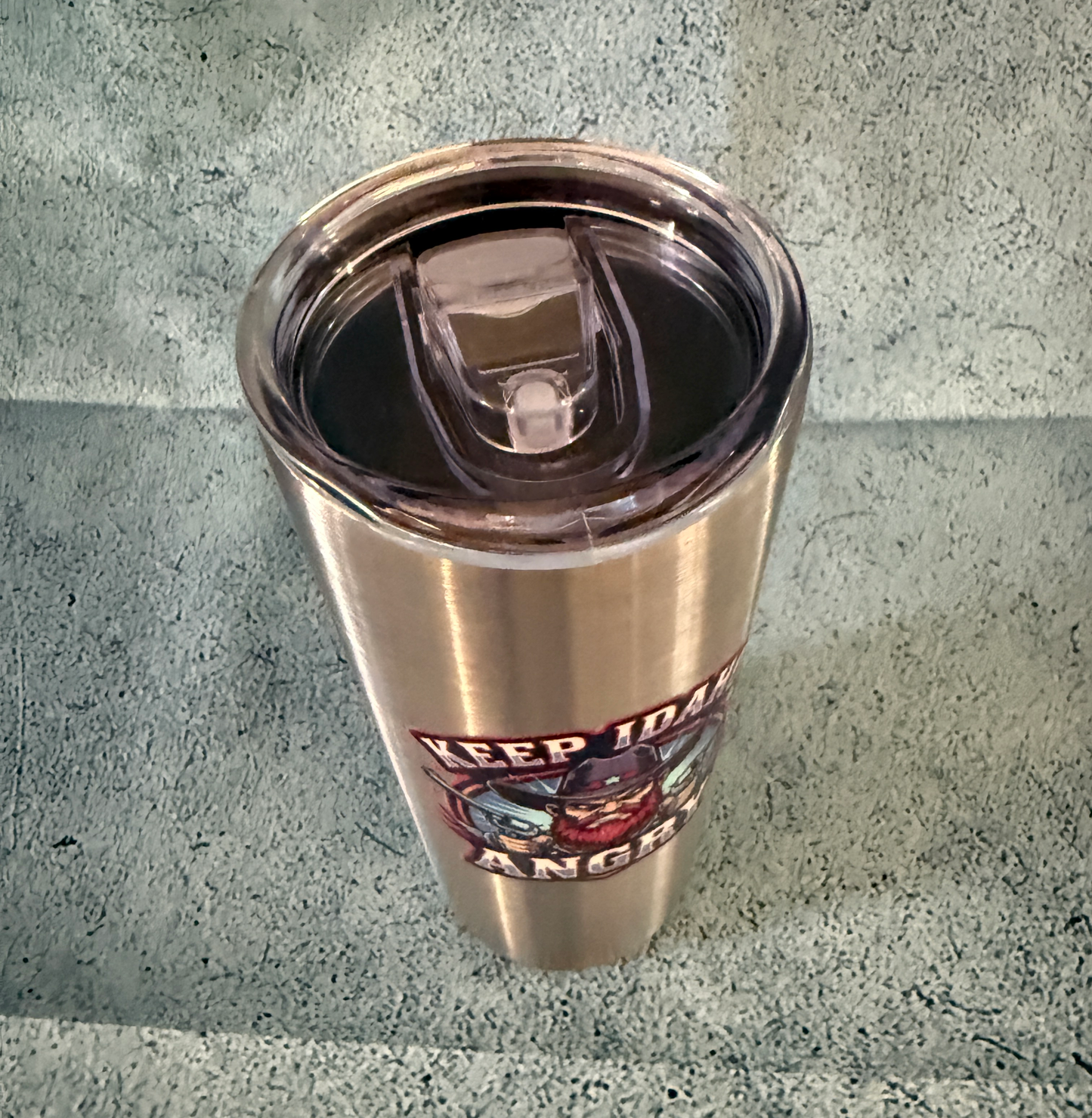 Stainless steel tumbler with a graphic design on a concrete surface