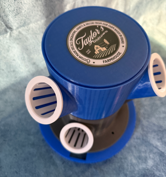 Blue cylindrical hydroponics unit with white pods on a textured gray background