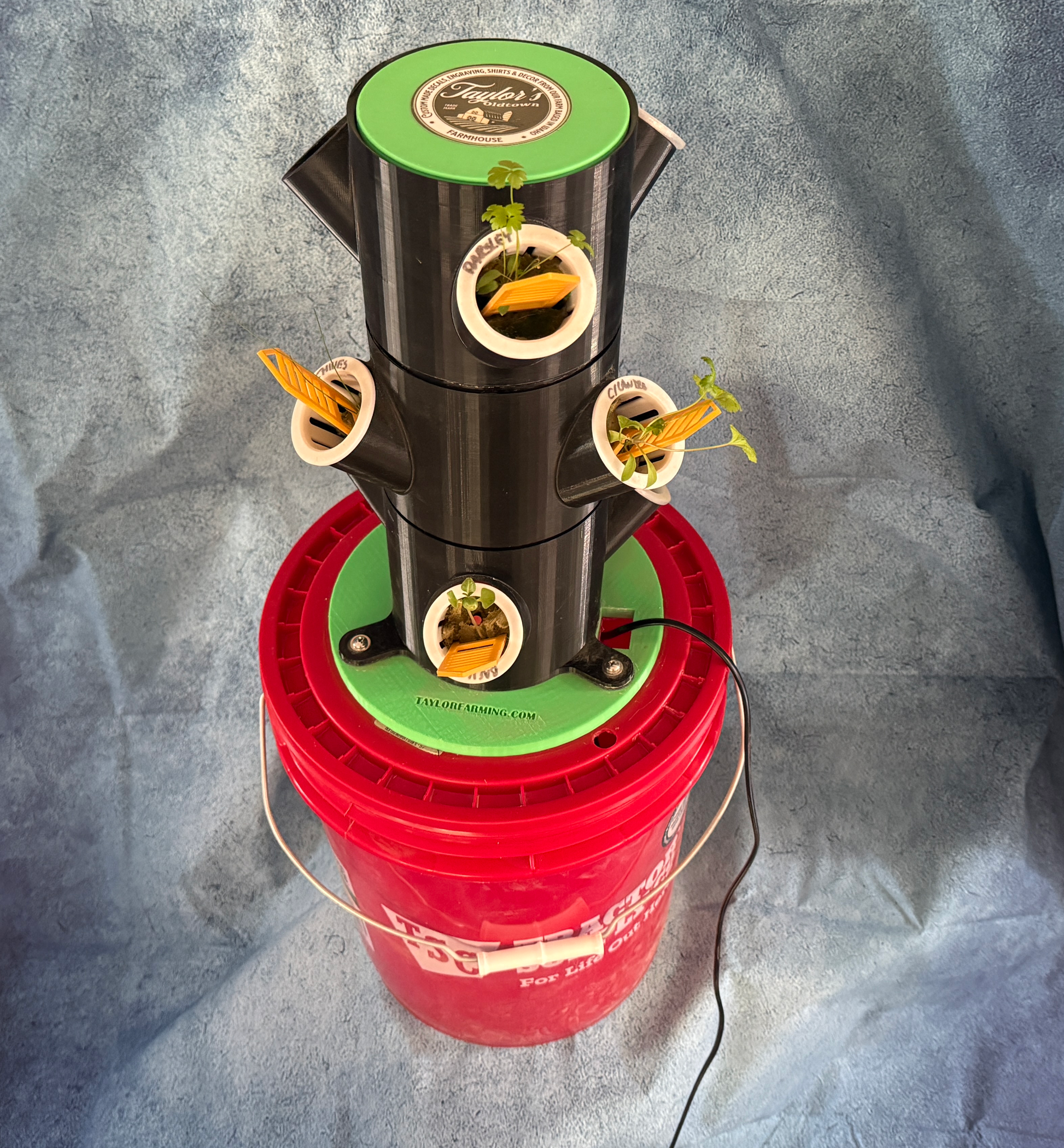 Vertical hydroponic garden on a red bucket against a gray background
