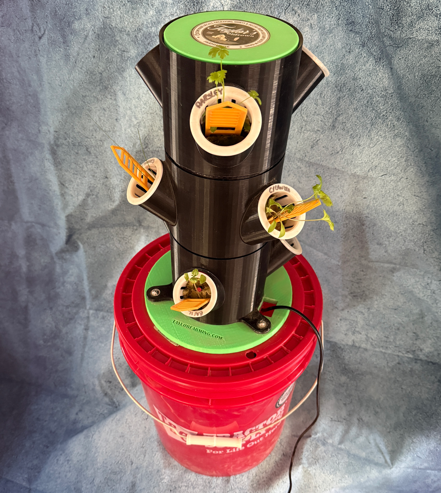 Vertical hydroponic garden system on a red bucket against a gray background